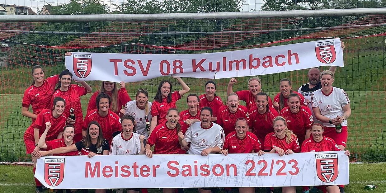 Unsere Frauenmannschaft feiert vor dem Tor mit Bannern die Meisterschaft der Saison 2022/23